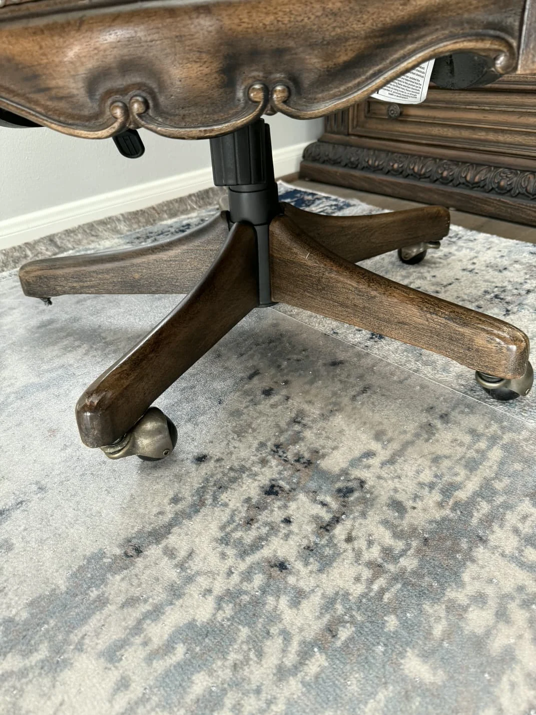 Broken and failed casters beneath a wooden home-office chair before repair.