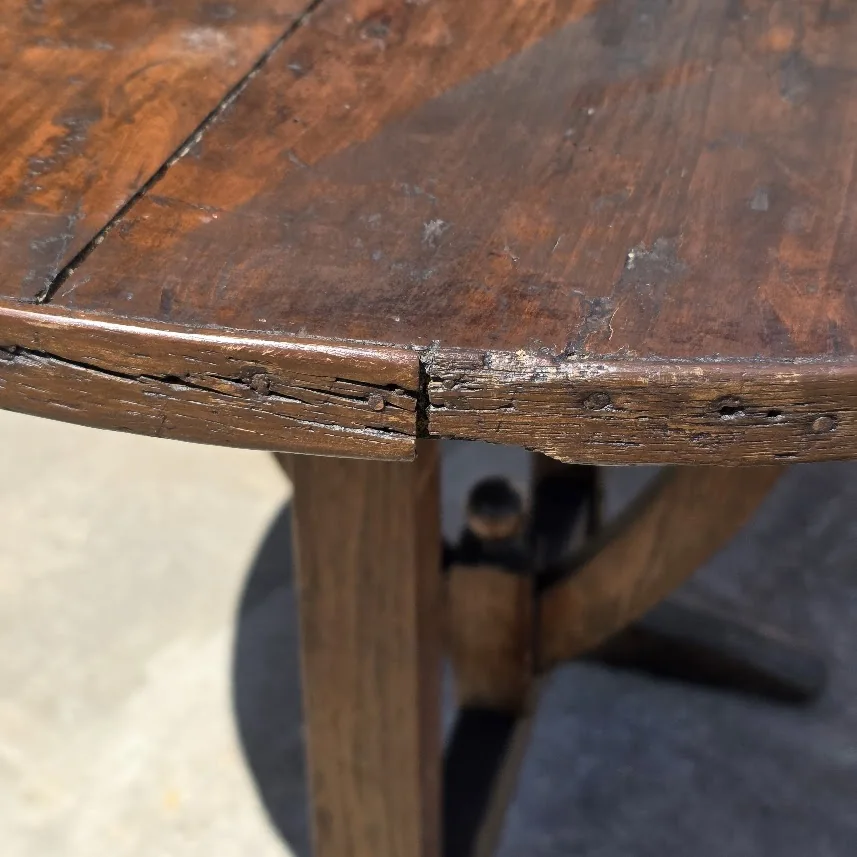 Close view of severe termite damage along the edge of a round wooden family table before reconstruction.