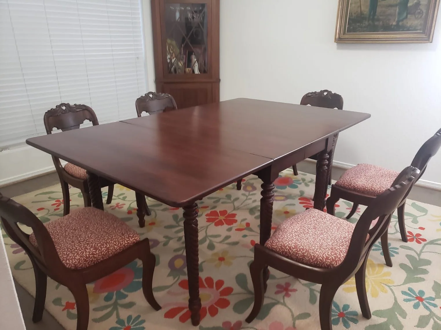 A refinished dark wood dining table with turned legs surrounded by matching chairs with red patterned upholstery.